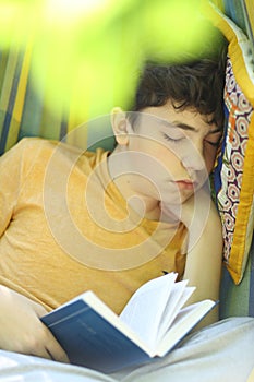 Teenager boy resting sleep with book in hammock on summer green garden