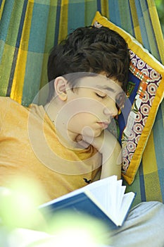 Teenager boy resting sleep with book in hammock on summer green garden