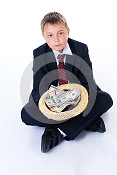 A teenager boy in school uniform holding a hat and begging for money