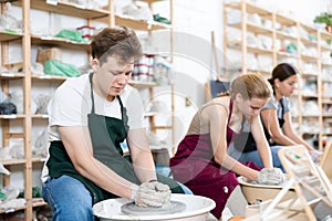 Teenager boy sculpts clay pottery on potter wheel