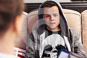 Teenager boy sitting at counseling - in front of the therapy professional, close up