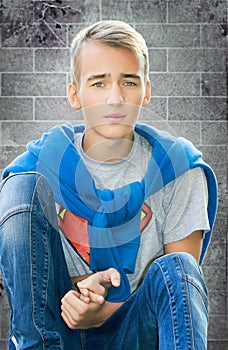 Teenager boy sitting at the wall closeup.