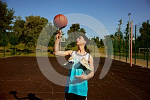 Teenager boy spinning basketball ball on finger over street court background