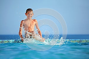 Teenager boy splashes feet water in pool