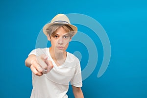 Teenager boy standing on blue isolated background pointing with finger to the camera and to you, hand sign, positive and confident