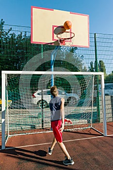 Teenager boy street basketball player on the city basketball court.