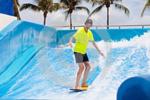 Teenager boy surfing in beach wave simulator