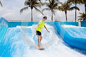 Teenager boy surfing in beach wave simulator