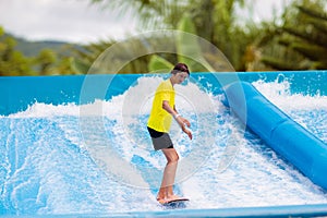 Teenager boy surfing in beach wave simulator