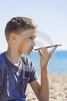 Teenager boy using a smart phone voice recognition function online, using cell phone to send a voice message on the