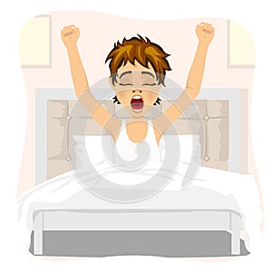 Teenager boy waking up stretching and yawning lying on bed