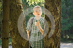 Teenager boy walking in the forest alone in the summer day