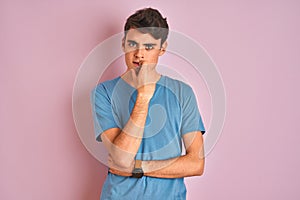 Teenager boy wearing casual t-shirt standing over blue isolated background looking stressed and nervous with hands on mouth biting