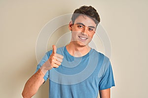 Teenager boy wearing casual t-shirt standing over isolated background doing happy thumbs up gesture with hand