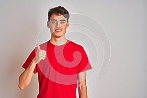 Teenager boy wearing red t-shirt over white isolated background doing happy thumbs up gesture with hand