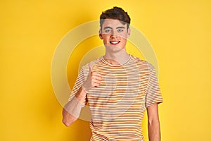 Teenager boy wearing yellow t-shirt over isolated background doing happy thumbs up gesture with hand