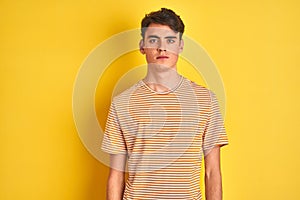 Teenager boy wearing yellow t-shirt over isolated background Relaxed with serious expression on face