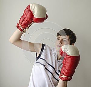 Teenager boy in a white shirt without sleeves and in boxing gloves