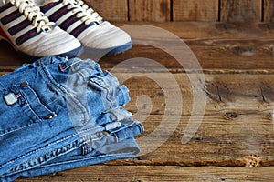 Teenager casual outfit. Boys shoes, clothing and accessories on wooden background - jeans, sneakers. Top view. Flat lay