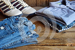 Teenager casual outfit. Boys shoes, clothing and accessories on wooden background - sweater, shirt, trousers, jeans, sneakers. Top