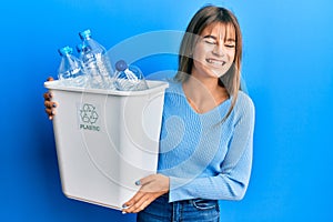 Teenager caucasian girl holding recycling bag with plastic bottles smiling and laughing hard out loud because funny crazy joke