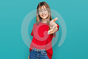 Teenager caucasian girl wearing casual red t shirt smiling friendly offering handshake as greeting and welcoming