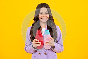 Teenager child girl showing bottle shampoo conditioners or shower gel isolated on yellow background. Hair cosmetic