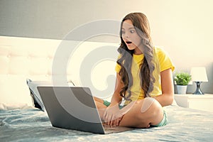 Teenager child girl working on laptop pc computer lying in bed resting relaxing in bedroom at home. teen girl. Surprised