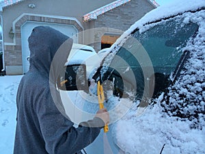 Teenager cleaning snow off a vehicle