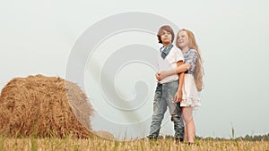 Teenager couple embracing on countryside field on haystack background. Young couple teenager girl and boy hugging on