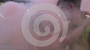 Teenager couple resting and relaxing in cloud of colored smoke, clubbing, slowmo