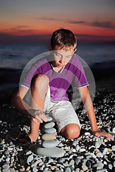 Teenager creates pyramid from pebble on seacoast