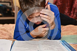 Teenager cries while solving a difficult school homework in a room on a bed