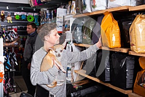 Teenager with dog choosing food in petshop