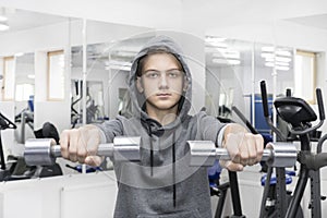 Teenager is engaged in bodybuilding in the gym.