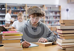 Teenager engaged in research working with books in library