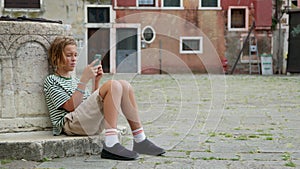Teenager Engrossed in Smartphone at Venetian Square