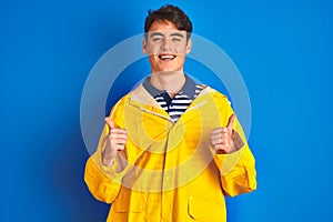 Teenager fisherman boy wearing yellow raincoat over  background success sign doing positive gesture with hand, thumbs up