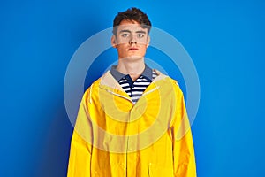 Teenager fisherman boy wearing yellow raincoat over isolated background Relaxed with serious expression on face