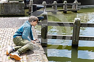 A teenager is fishing on a canal in Amsterdam