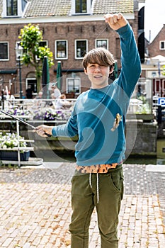 A teenager is fishing on a canal in Amsterdam