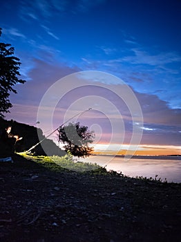 teenager with a fishing rod fishing on the river bank in nature