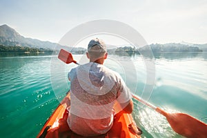 Teenager floating on kayak on calm water on Cheow Lan Lake, Khao Sok national park, Thailand