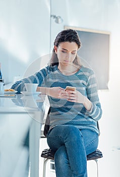 Teenager girl at the bar texting with her mobile