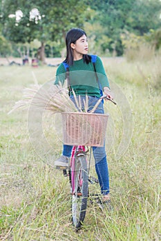 Teenager girl, bicycle with flowers basket in outdoor landscape