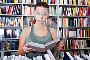 Teenager girl brunete looks for the right book in library