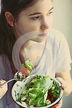 Teenager girl with cut cucumber tomato salad bowl