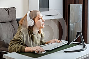 Teenager girl cybersportman gamer play online computer game at home alone in leisure time. Young blonde woman in