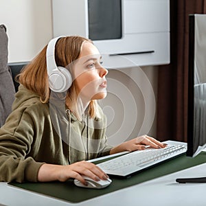 Teenager girl cybersportman gamer play online computer game at home alone in leisure time. Young blonde woman in