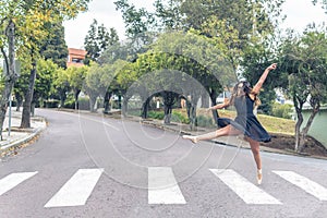 Teenager girl dancing with ballet shoes on a pedestrian crossing in the street